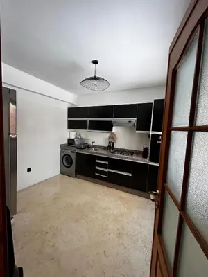 an empty kitchen with black cabinets and a door at Charmant Appartement à Gueliz in Marrakech