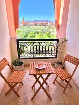 a table and two chairs on a balcony with a view at Appartement LILIA in Marrakech