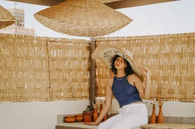 a woman sitting on a bench wearing a straw hat at Riad Shabi Kasbah in Marrakech