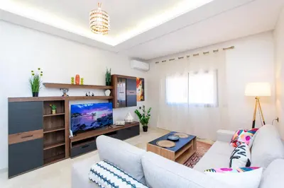 a living room with a couch and a tv at Appartement en résidence fermée in Marrakech