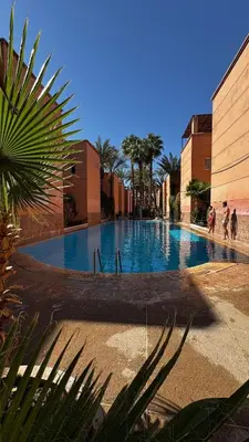 a large swimming pool with people walking around it at Riad Beldi Chic Un Séjour Authentique Proche Médina in Marrakech