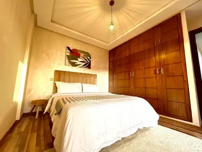 a bedroom with a bed and wooden cabinets at Le Cocon doré avec terrasse ensoleillée au centre de Marrakech in Marrakech
