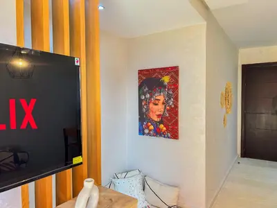 a living room with a tv and a painting on the wall at Le Cocon doré avec terrasse ensoleillée au centre de Marrakech in Marrakech