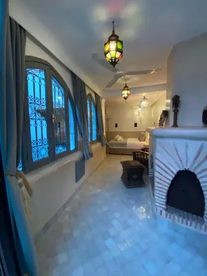 a living room with a fireplace and a bedroom at Riad DAR OMI ZAHRA in Marrakech