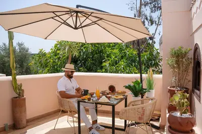 a man sitting at a table under an umbrella at Riad Yalla habibi in Marrakech