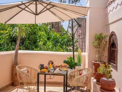 a patio with a table and chairs and an umbrella at Riad Yalla habibi in Marrakech