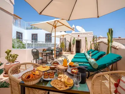 a table with food on a patio with umbrellas at Riad Yalla habibi in Marrakech
