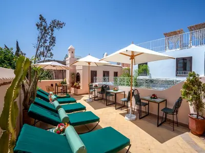 a patio with green benches and tables and umbrellas at Riad Yalla habibi in Marrakech