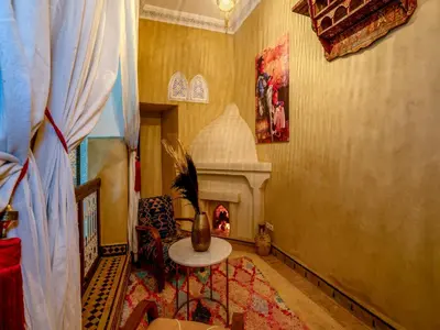a living room with a fireplace and a table at Riad Yalla habibi in Marrakech