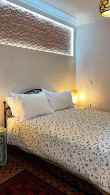 a bedroom with a bed with white sheets and a window at Raid Maison H in Marrakech