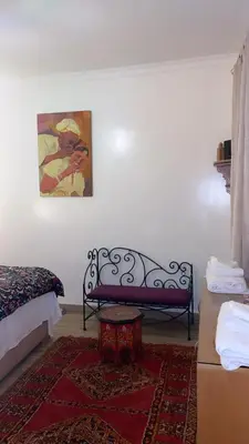a bedroom with a bench and a painting on the wall at Raid Maison H in Marrakech