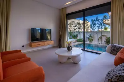 a living room with a couch and a tv and a table at Villa Piscine Privée, Petit déjeuné et ménage inclus in Marrakech