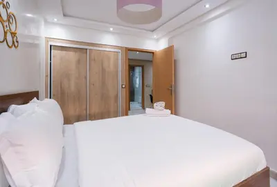 a bedroom with a white bed and a wooden door at Bright Flat in Heart of Center in Marrakech