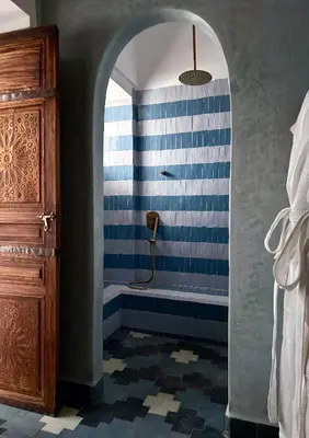 a bathroom with a shower with a blue and white stripes at Riad Jalma in Marrakech