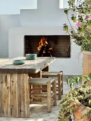 a table and chairs in front of a fireplace at Riad Jalma in Marrakech