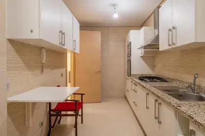 a kitchen with white cabinets and a red chair at Luxury XL Appart Golf View Retreat Private Garden in Marrakech