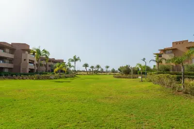 a large green field with palm trees and buildings at Luxury XL Appart Golf View Retreat Private Garden in Marrakech