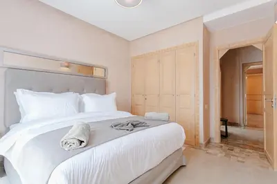 a bedroom with a large white bed with towels on it at Villa Atlas Harmony Marrakech in Marrakech