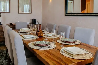a long wooden table with chairs and wine glasses at Villa Atlas Harmony Marrakech in Marrakech