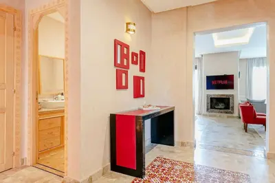 a living room with a red table and a fireplace at Villa Atlas Harmony Marrakech in Marrakech
