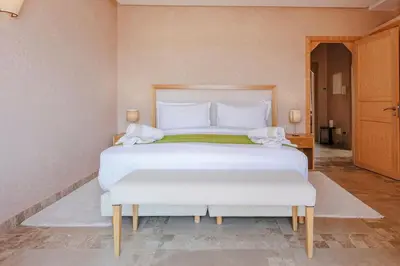 a bedroom with a large white bed with two white seats at Villa Atlas Harmony Marrakech in Marrakech