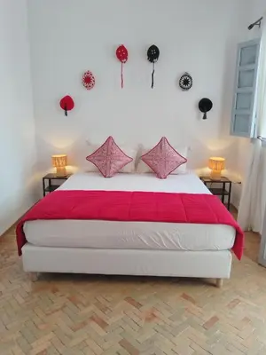 a bedroom with a large white bed with red sheets at Riad L'Arganier in Marrakech