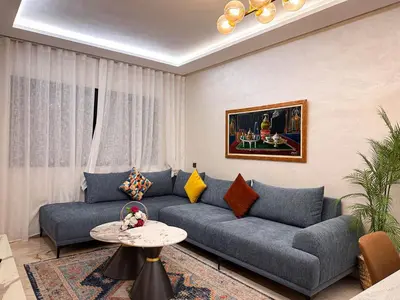 a living room with a blue couch and a table at Appartement de Luxe bien équipé in Marrakech