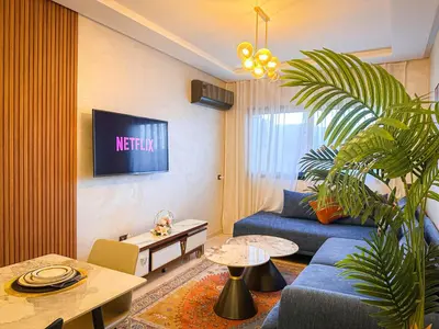 a living room with a blue couch and a tv at Prestigieux Appartement in Marrakech