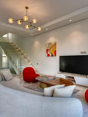 a living room with a large television and a red chair at villa argan golf piscine chauffée in Marrakech