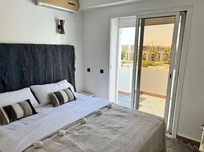 a bedroom with a large bed and a sliding glass door at Appartement sur Majorelle in Marrakech