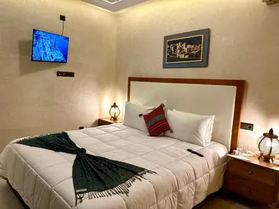 a bedroom with a large bed and a tv on the wall at Riad Tislite & SPA in Marrakech
