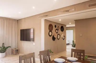 a dining room with a table and chairs and a television at Designer Gueliz Penthouse - Terrace - Atlas Views in Marrakech