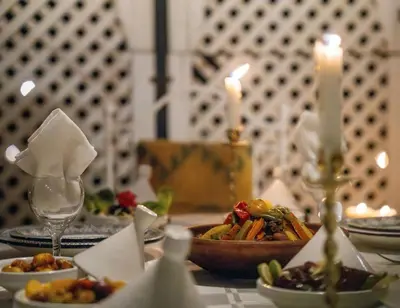 a table with plates of food on a table with candles at Authentic house in the old Medina of Marrakech in Marrakech