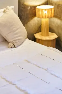 a white bed with a lamp on a table at Riad Kbala in Marrakech