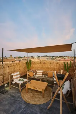 a patio with chairs and a table and a umbrella at Riad Kbala in Marrakech