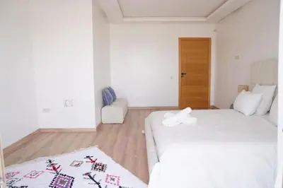 a white room with two beds and a chair at Villa Home Orient Avec Piscine Privée 3 Chambres in Marrakech