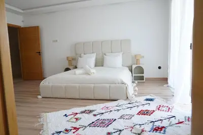 a white bedroom with a white bed and a rug at Villa Home Orient Avec Piscine Privée 3 Chambres in Marrakech