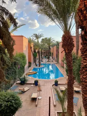 a swimming pool in a resort with palm trees at Amazing 3 Bedroom Riad Marrakech in Marrakech