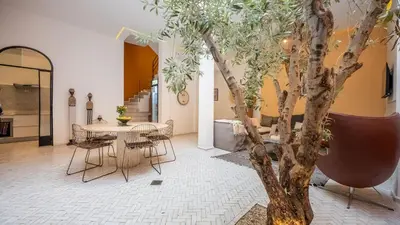 a room with a table and chairs and a tree at Riad Jarco Marrakech, cœur Medina, Rooftop, bassin , Proche Place Jemaa el fna in Marrakech