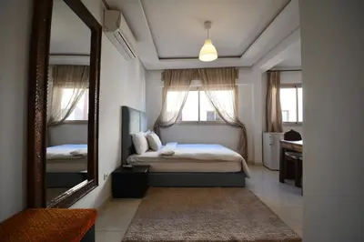 a small bedroom with a bed and a mirror at Studio chic cosy au centre de l'hivernage marrakech in Marrakech