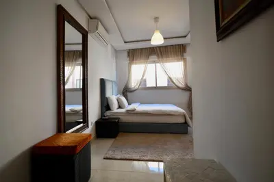 a bedroom with a bed and a large mirror at Studio chic cosy au centre de l'hivernage marrakech in Marrakech