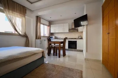 a bedroom with a bed and a kitchen with a table at Studio chic cosy au centre de l'hivernage marrakech in Marrakech