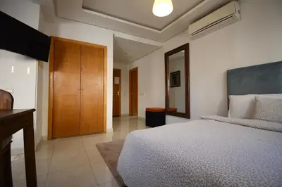 a bedroom with a bed and a wooden cabinet at Studio chic cosy au centre de l'hivernage marrakech in Marrakech