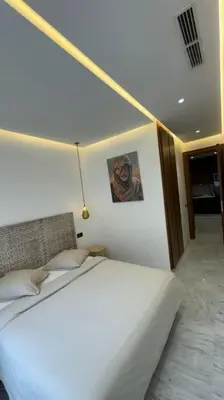 a bedroom with a white bed with a picture on the wall at Appartement neuf et cosy au coeur de Guéliz in Marrakech