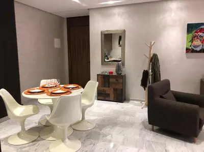 a dining room with a table and white chairs at Appartement neuf et cosy au coeur de Guéliz in Marrakech