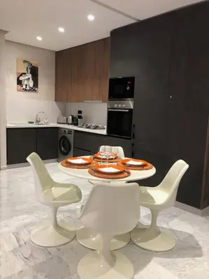 a kitchen with a table with white chairs and a tableasteryasteryasteryasteryastery at Appartement neuf et cosy au coeur de Guéliz in Marrakech