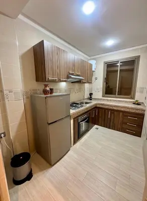 a kitchen with wooden cabinets and a refrigerator at The Blue Pearl - Fresh & Modern in Marrakech