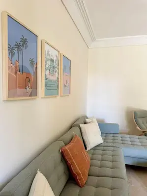 a living room with a green couch and pictures on the wall at Somptueux appartement jardin & piscine - Hivernage in Marrakech