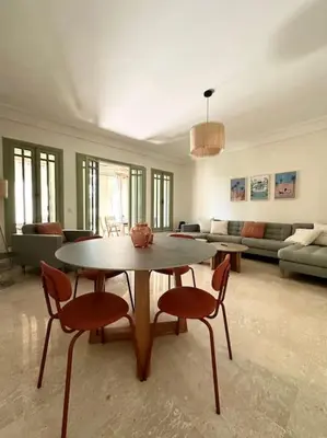 a living room with a table and chairs and a couch at Somptueux appartement jardin & piscine - Hivernage in Marrakech