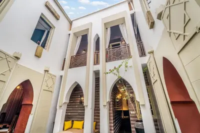 a large white building with arches and windows at Riad EYNA Marrakech Medina in Marrakech